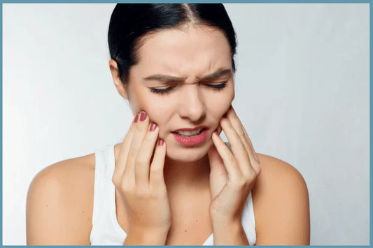 Young woman holding her jaw in pain from tooth sensitivity often caused by peroxide whitening strips.